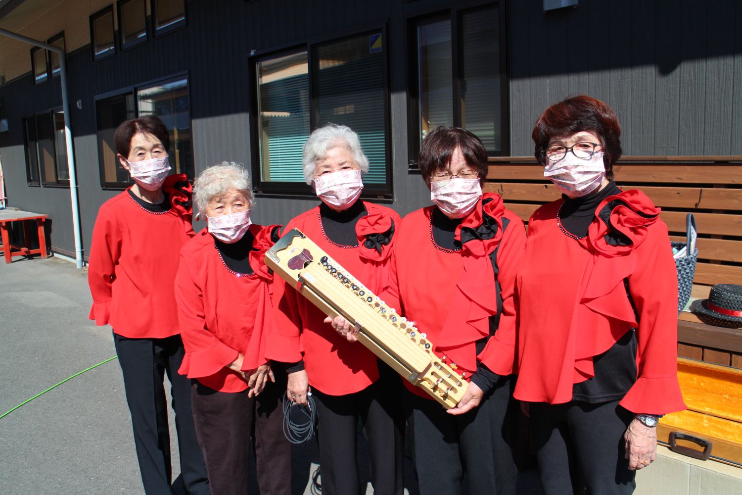 赤い揃いの衣装を着た「南三陸大正琴の会」のみなさんが、大正琴を手にして写っている集合写真