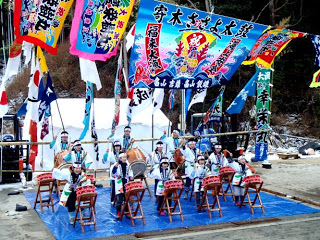 色とりどりの大漁旗が風になびく会場のステージで、揃いの衣装を着て、子どもたちが和太鼓の演奏を披露している写真