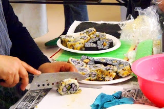 参加者が包丁で巻き寿司を切って盛り付けた皿に、色とりどりの飾り巻き寿司が並ぶ写真