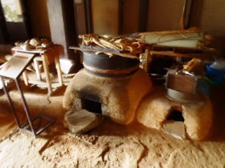大きさの違うかまどが横に2つ並び、色々な昔の道具が展示されている様子を写した写真