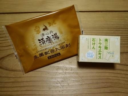 木製のテーブルの上に、茶色いパッケージに入った「清癒湯」という入浴剤と、白い箱に緑色の文字で「南三陸トウキエキス石けん」と書かれた石鹸が並べて置かれている写真