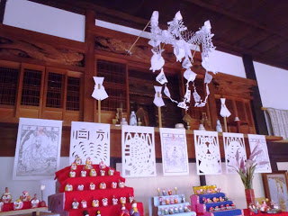 神棚に紙垂とともに白い紙で作られた『きりこ』が複数貼られ、5段や3段の小さな雛飾りがいくつも展示されている写真