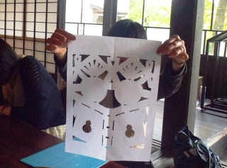 神酒をかたどった模様が浮かび上がった「きりこ」を両手で持ち上げて見せている写真