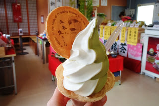 抹茶とバニラのミックスソフトクリームにモアイの絵と英語・日本語のメッセージが焼き印されたイラスト入りの円盤ウエハースが添えられた写真