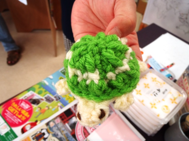 緑と白の毛糸で編まれた子亀のアクリルたわしの写真