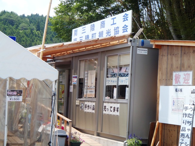 「南三陸商工会 南三陸町観光協会」と書かれた看板が掲げられたプレハブの建物があり、窓の下には「手作り品売ってます」などの貼り紙がされている「うたちゃんショップ」の外観写真