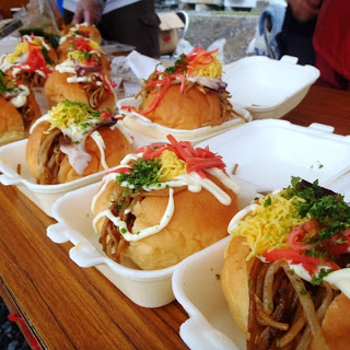 ふんわりしたパンに焼きそば、紅しょうが、マヨネーズ、錦糸卵、青のりなどがたっぷりトッピングされ、発泡容器にずらりと並べられた、屋台で販売されている彩り豊かな焼きそばパンの写真