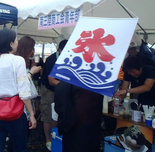 「氷」の旗が出店にかけられ、お客さんたちが並んでかき氷を注文している、南三陸商工会青年部による夏らしい屋台の写真