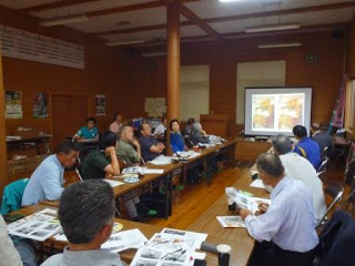 スクリーンに二つの作品の写真が映し出され、参加者が資料を手に意見交換をしている写真