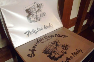 アルバムのようにめくれる紙に、英語の文字と古い機械のようなイラストが描かれているデザイン画の写真