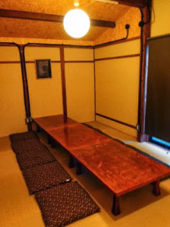 座布団が並べられた長テーブルがあり、和室の雰囲気を持つ部屋の写真