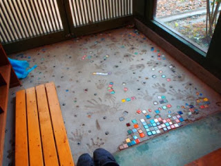 床にカラフルな小さなタイルが埋め込まれ、子供の手形や足形の跡が残っている玄関の床のアップ写真