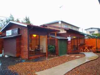 木造の平屋建ての店舗で、前庭には石畳の小道が伸び、右側に木製のテーブルと椅子が置かれている居場所 心家の外観写真