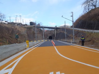 手前は道路がオレンジ色に舗装され、まっすぐにトンネルまで伸びている整備された専用道の写真