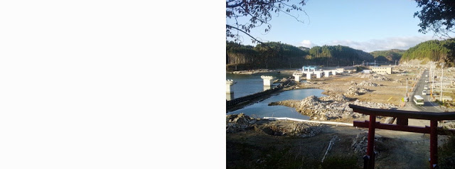 鳥居の前に道路が通り左側の入り江には橋の橋脚だけが立ち並んでいる側にかコンクリート等の瓦礫が広がっている写真