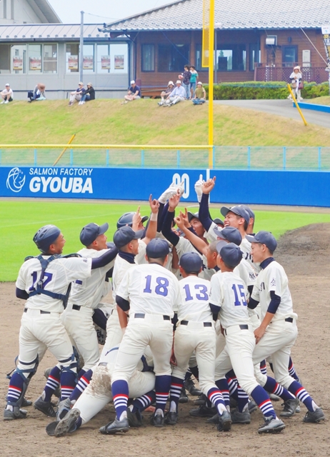 勝利を喜ぶ選手たちがマウンド上でユニフォーム姿のまま輪になり、全員で拳を突き上げて歓喜を爆発させている写真