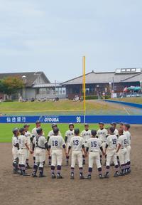 高校野球の選手たちが、ユニフォーム姿でマウンド付近で手を繋いで大きな輪をになり、声を出している様子の写真