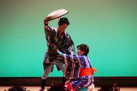 舞台の上で伝統的な和服を着た二人が、扇を使った演舞を披露している写真