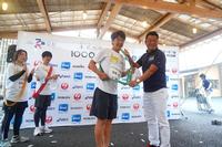 「宮城-8」のゼッケンをつけた男性が、首から下げた緑色のタスキをネイビー色のポロシャツを着た男性と一緒に持って記念撮影をしている写真