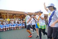 青い衣装を着た園児たちが見守る前を笑顔で走っているランナーたちの写真