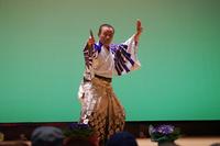 舞台の上で和装の男性が扇子を持って踊っている様子の写真