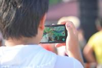 スマートフォンでライブパフォーマンスを撮影している男性の後ろ姿の写真