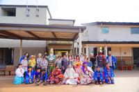 平安時代風の衣装を着た演者や観客の大人と子どもが集合し、屋外で記念写真を撮っている写真