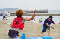 浜辺で赤と青のビブスを着た2人が水を使ったスポーツゲームをしているアクティビティの写真