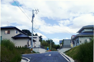 左右に完成した住宅が並び、中央の舗装道路が奥に続いている整った町並みの写真
