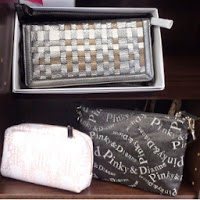 白い箱に入った編み込み模様のシルバー系長財布と、白と黒のオリジナルデザインポーチが棚に並べて陳列されている写真