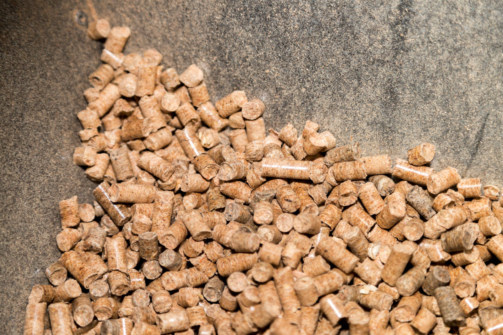 木のチップを固めた小さな円筒状の木質ペレットが大量に金属製の容器に入っている様子をアップで撮影した写真