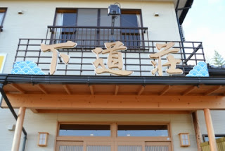 建物の玄関部分に大きな文字で「下道荘」と書かれた看板が掲げられている宿の正面玄関の写真