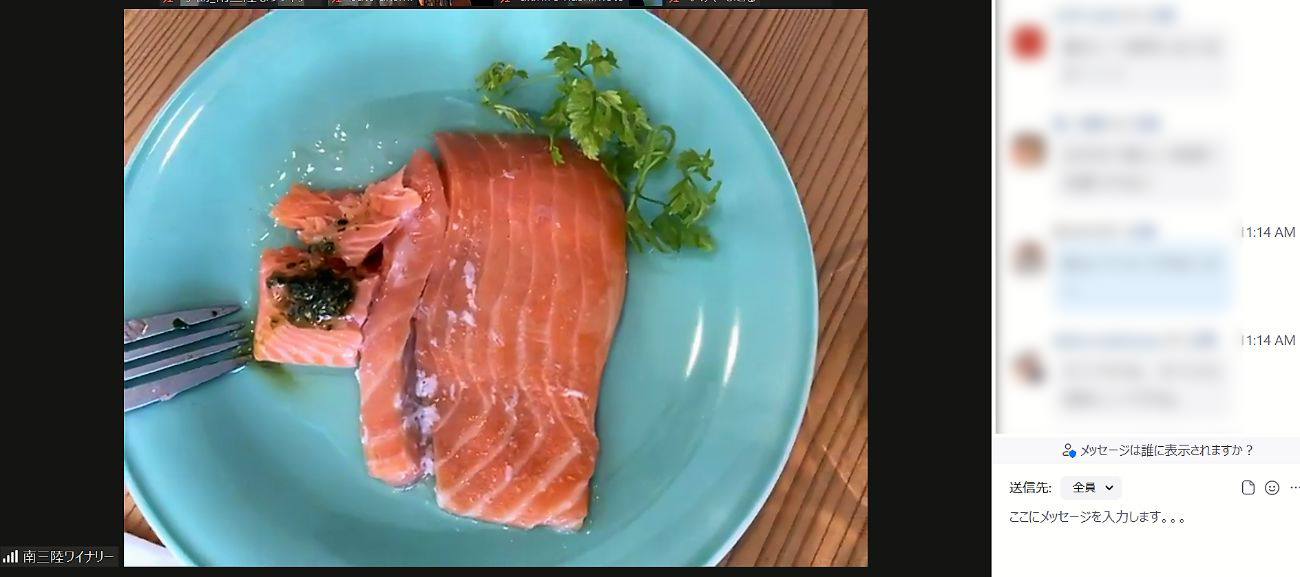 水色の皿にオレンジ色の銀鮭のコンフィが乗っており、フォークでカットした左端の上にバジルペーストがトッピングされているパソコン画面の写真