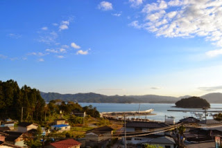 穏やかな海と湾を見下ろす高台から、集落と山々が広がる風景を撮影した美しい眺望の写真
