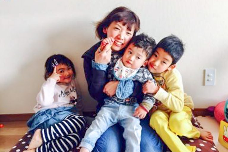 母親が中央で、左右に小さな子どもたちとくつろいでいる写真