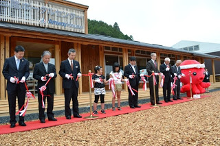 スーツ姿の関係者や子どもたちが並び、赤いじゅうたんの上でテープカットをしている「南三陸ポータルセンター アムウェイハウス」オープニングイベントの写真