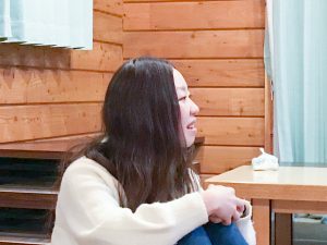 床に座って横を向きながら楽しそうに話をしている阿部菜央さんの写真