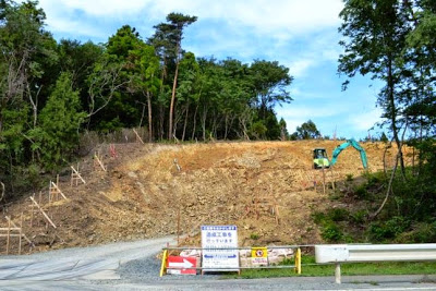 木々を切り開いて斜面を削った造成地に重機が置かれている様子が写っている造成工事中の写真