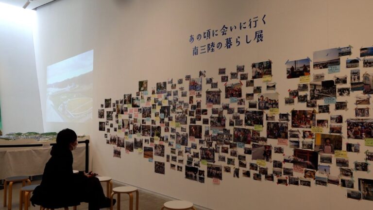 白い壁一面に「南三陸の暮らし展」と題された多数の写真が貼られ、訪れた人が椅子に座って静かに眺めている、震災前後の記憶や地域の営みを伝える南三陸町の写真展の写真