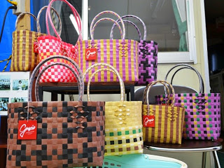 さまざまな色と模様で編まれた手作りのかごバッグが、棚や椅子の上にきれいに並べられている室内の写真