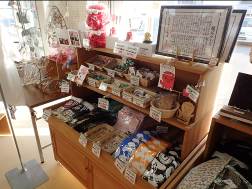 木製の2段の陳列棚にそれぞれポップが貼られ、さまざまな種類の商品が並べられている店内の写真