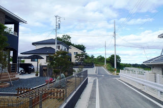 整備された住宅街で新築の住宅が建ち並び、道路の両側に電柱が立つ静かな町並みの写真