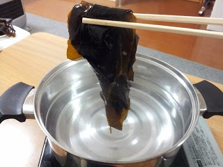 お湯がはいった鍋に生わかめを箸で入れようとしている写真