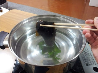 お湯のはいった鍋に半分くぐらせた生わかめの写真