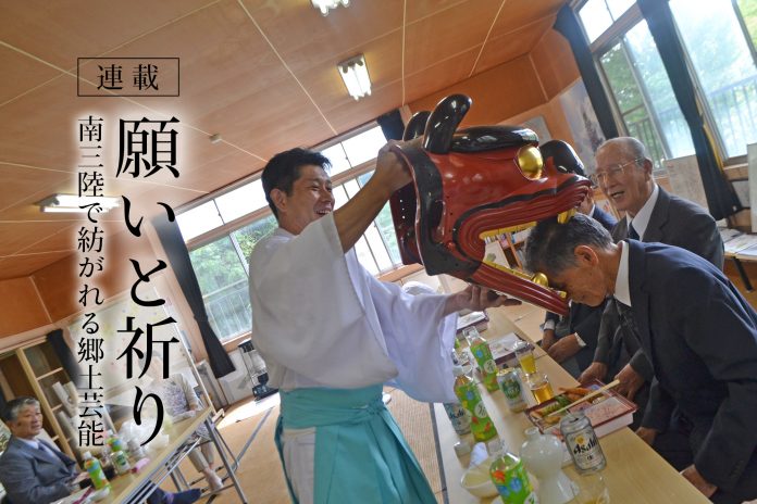 白衣と袴を着た工藤庄悦さんが獅子頭を使い、座っている年配の男性の頭を優しくかぶせている和やかな雰囲気の様子を捉えた写真