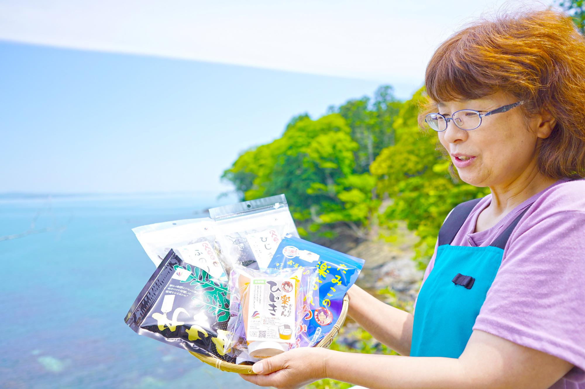 志津川湾を背景にカゴにのせた商品を持っている女性を撮影した写真