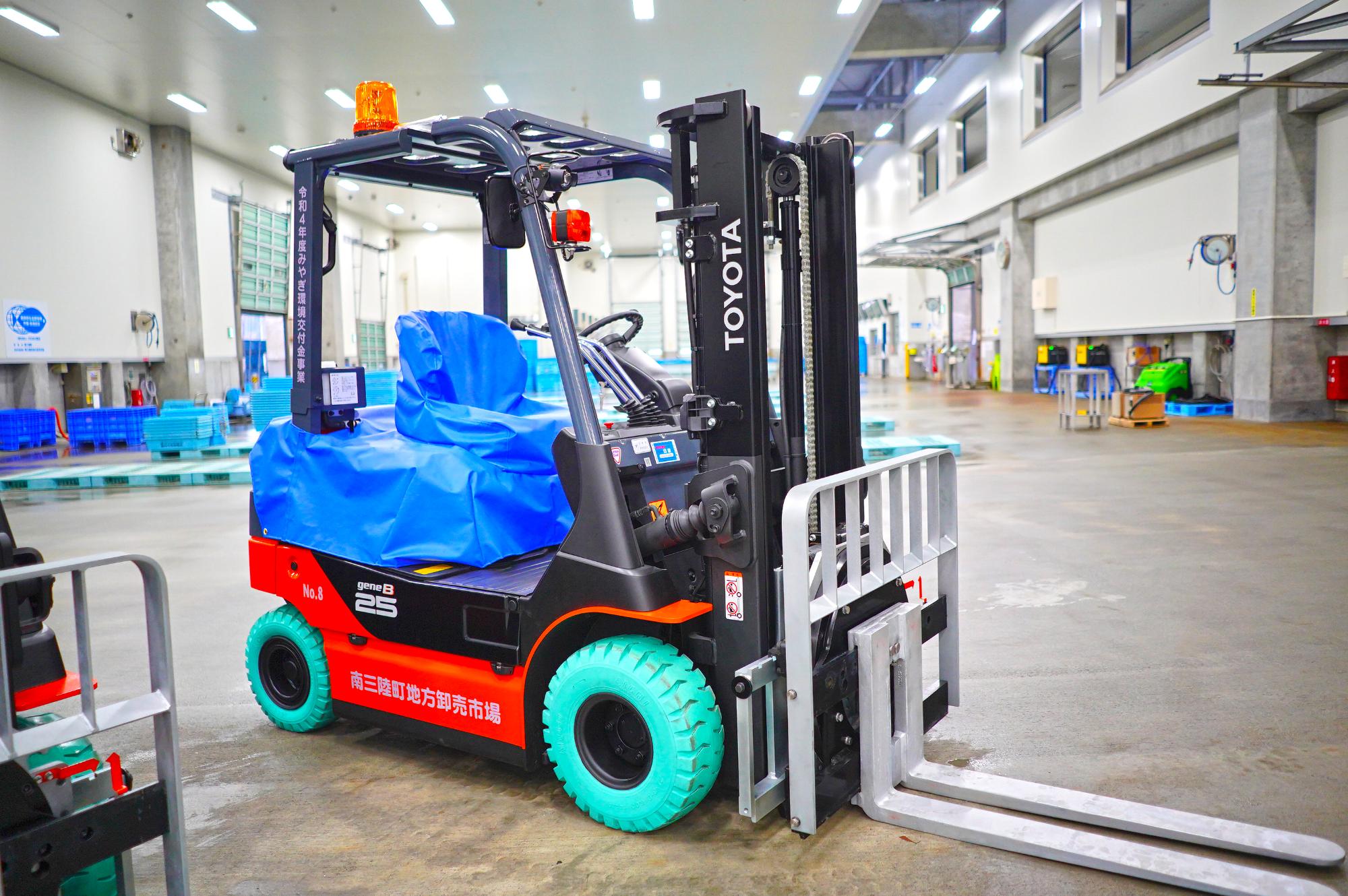 明るい倉庫の室内に置かれた1台の電動フォークリフトをアップで写した写真