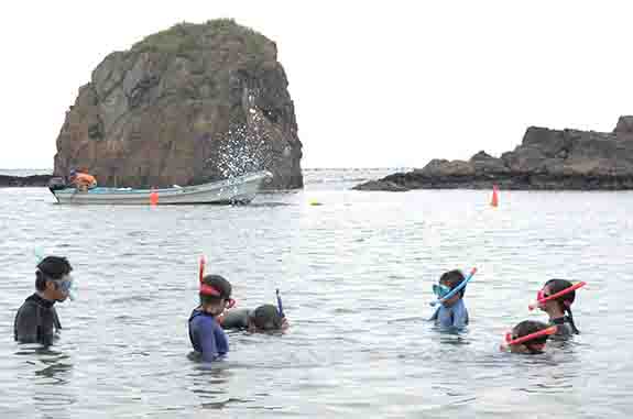 マスクを付けて海に入った子供たちがスノーケリング体験を行っている様子の写真