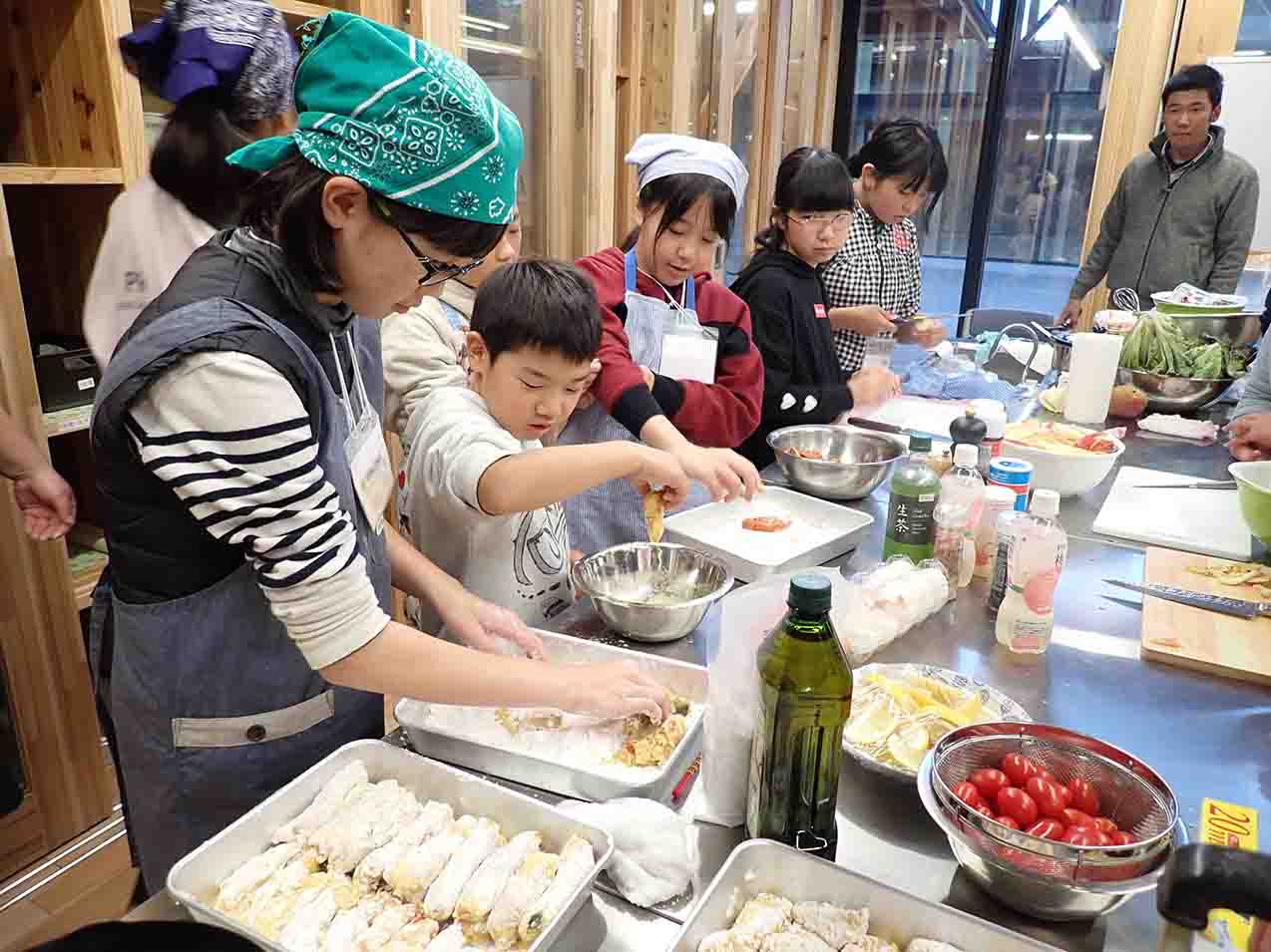 子どもたちと大人が一緒に料理をしている様子の写真
