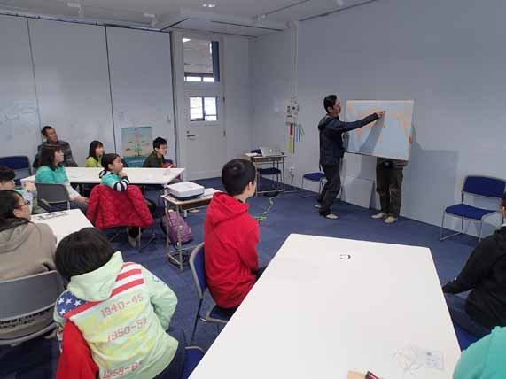 鈴木会長が指差し説明を行っている様子を子供たちが聞きコクガンのレクチャーを受けている写真